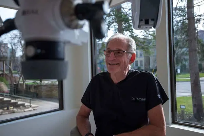 Dr. Manfred Friedman smiling beside the operating microscope